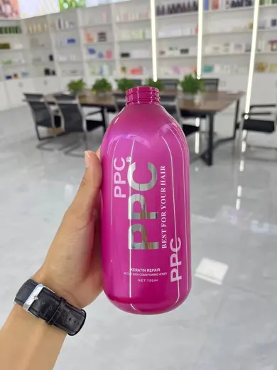 Chai nhựa dầu gội màu hồng đậm in chữ cầm trên tay
