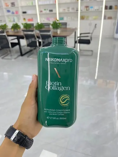 Chai dầu gội nhựa xanh lá in nhãn cầm trên tay